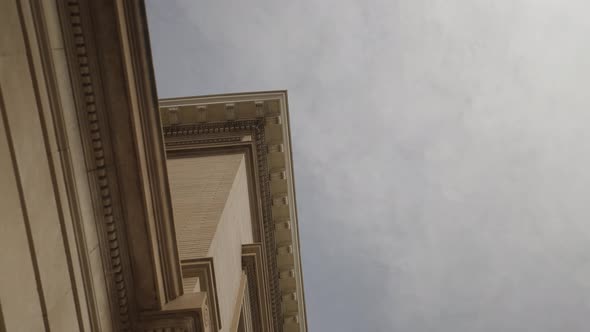 Looking up at the exterior brick architecture of a 1900's mansion with sky and clouds in background