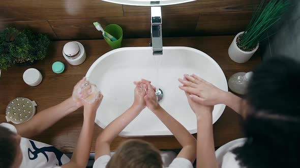 Woman with Black Hair and Two Her Sons which Washing Their Hands in the Washbasin