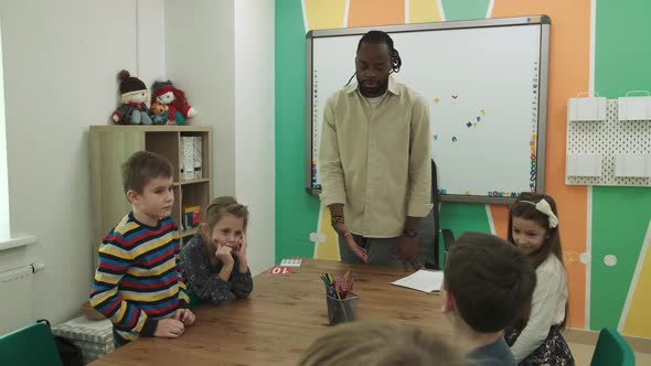 African American Teacher Teaches a Group of Children Aged 610 in a Classroom