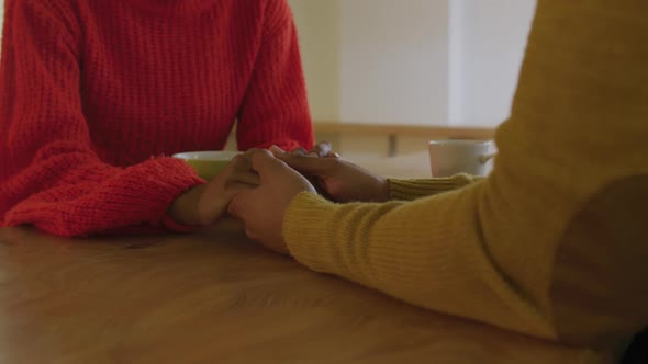 Millennial couple sitting holding hands at home