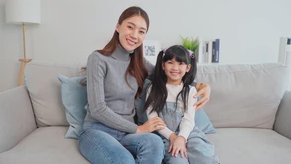 Asian happy family,  Happy Young girl daughter sit with Mother on sofa in living room and smile.