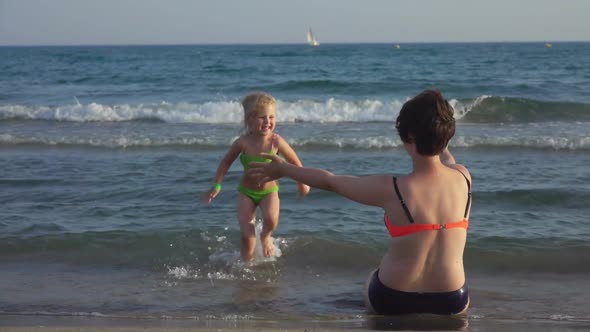 Mom and Daughter in Swimsuits Are Hugging on the Seashore