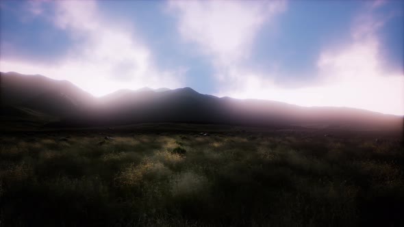 Sunset Over a Green Grassy Rocky Hills