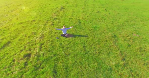 Low Orbital Flight Around Man on Green Grass with Notebook Pad at Yellow Rural Field