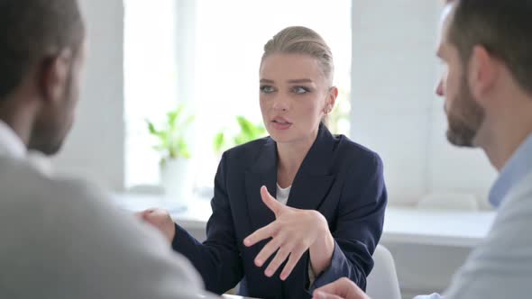 Serious Businesswoman Talking to Male Colleagues in Office