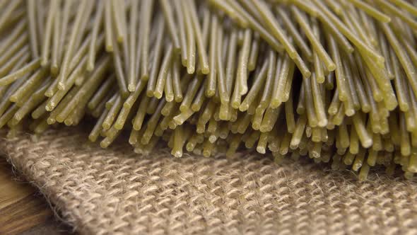 Green dry uncooked bio spaghetti on rough rustic sackcloth