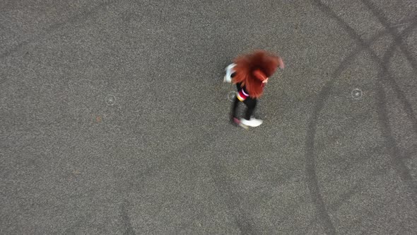 Birds Eye Aerial View of Young Red Haired Woman Riding Roller Skates,  Top Down Drone Shot