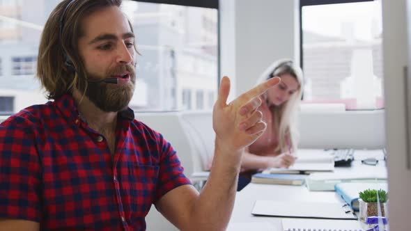 Caucasian business people wearing headphones talking to customers in modern office