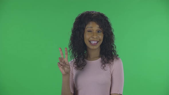 Portrait of Beautiful African American Young Woman Is Looking at Camera and Showing Two Fingers