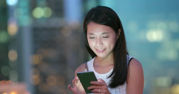 Woman use of mobile phone in the city at night