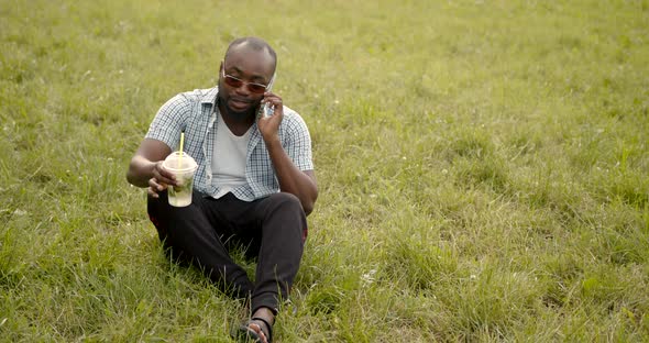 Joyful Handsome Black Male Sitting on the Grass