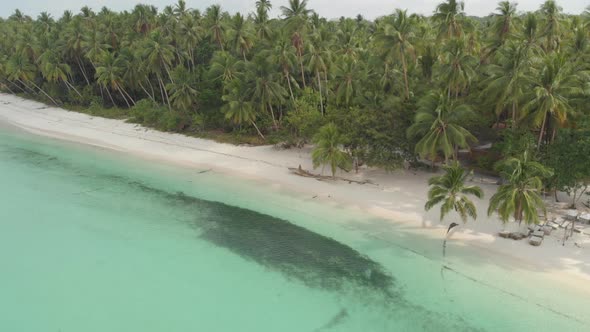 Aerial: woman relaxing on white sand beach turquoise water tropical