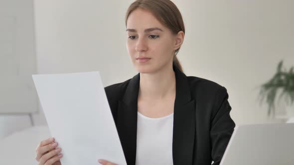 Young Businesswoman Reading Documents at Work