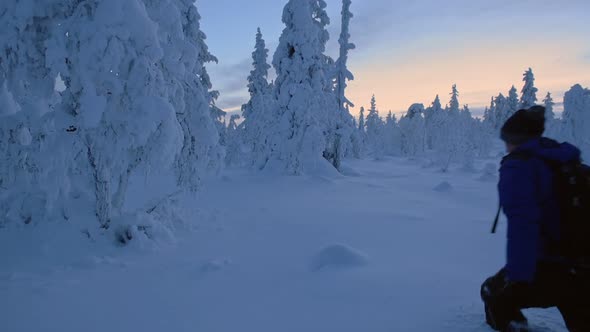 A Man With A Backpack Walking Along The Knee Deep Snow In The Region Of Lapland. -wide shot