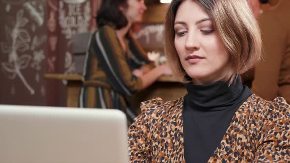 Woman Sips Some Coffee While Working in a Crowded Cafe