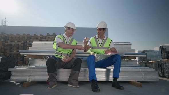 Wide Shot Portrait of Positive Caucasian and Middle Eastern Workers Sharing Lunch Sitting Outdoors