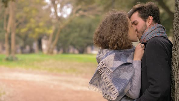 Love,Romance,passion.Attractive lovers kissing under a tree in the park