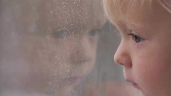 Sad Look Child Looking Out Window in Rainy Weather Water Droplets on Glass