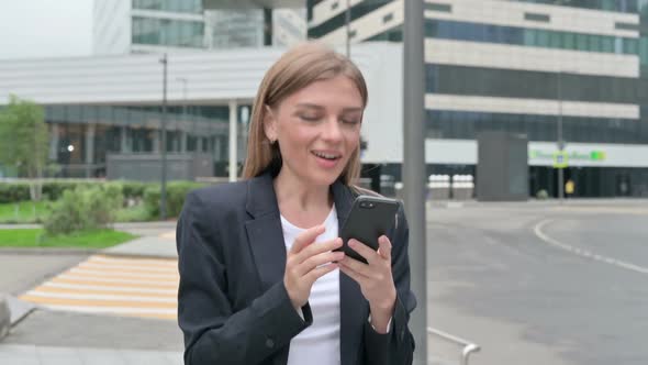 Businesswoman Celebrating on Smartphone While Walking on the Street