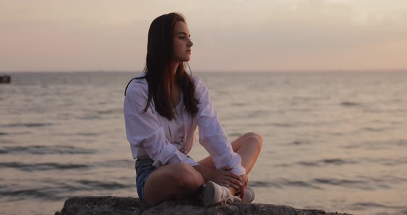 Young Woman Looks at the Sea Sunset Sitting on a Hill