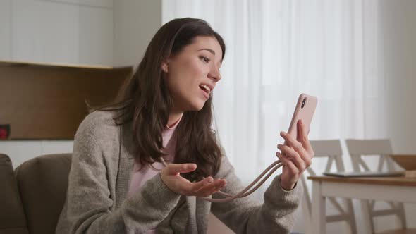 Young Caucasian Woman Greeting Her Friends or Family on a Video Call Using Pink Smart Phone