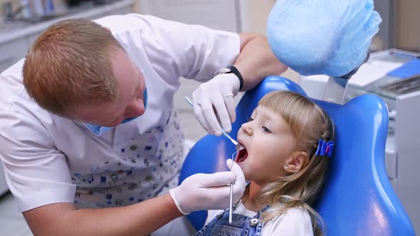 Little child in stomatology chair - close up. Cute blonde girl opened her mouth for teeth check up. 