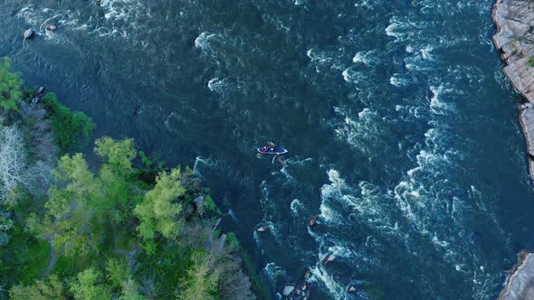 Aerial View of a Kayak Floating on a Turbulent River Between Forest and Stone Cliffs