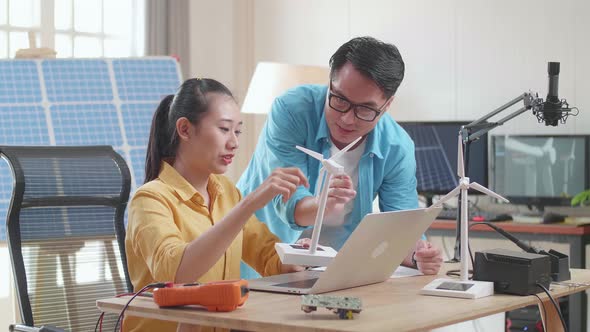 Asian Man And Woman Discuss About Work With Wind Turbine And Laptop Computer
