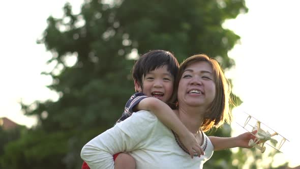 Cute Asian Mother And Son Playing Wooden Airplane Together In The Park Outdoors 