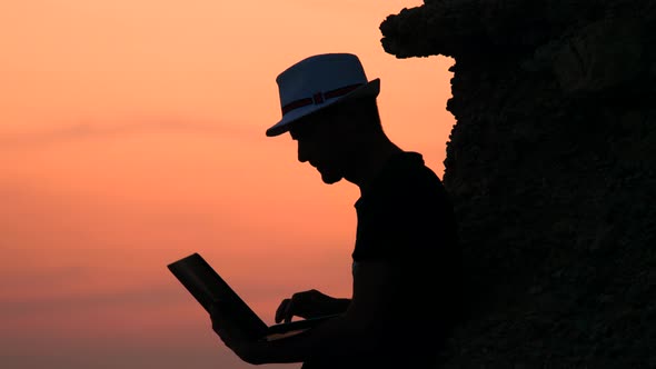 Preparing To Pitch. Male Freelancer Hipster with a Laptop Remote Work on the Beach on the Sunset