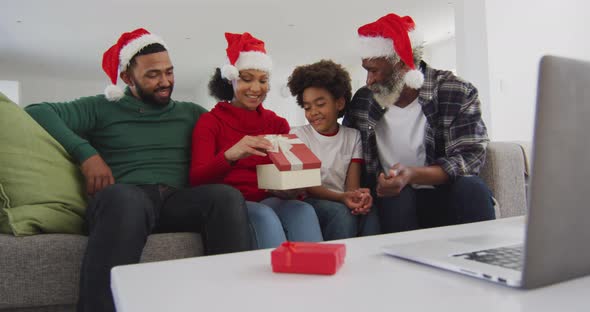Multi-generation family opening gift box while having video chat on his laptop