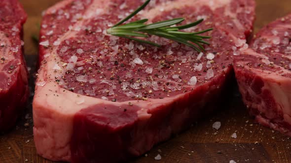 Seasoning raw ribeye beef steaks with rosemary