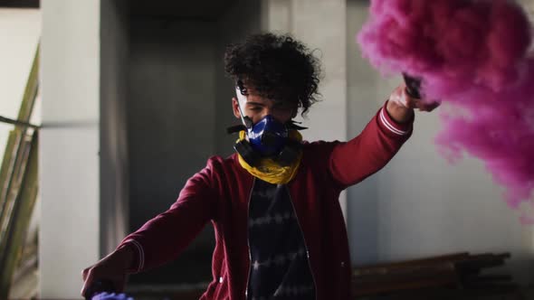 Mixed race man holding blue and purple flares standing in an empty building