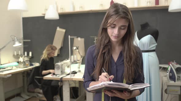 Beautiful Caucasian Female in Dark Blue Shirt and Long Brown Hair Making Notes Showing Ok Standing