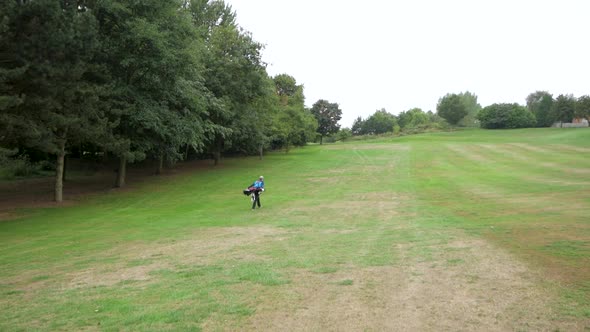 Wide shot of a golfer walking towards the green after a shot.