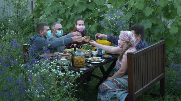 Family in protective medical masks at picnic at summer house in village. Relatives together