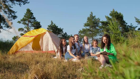 The Camp Counselorr Works with a Group of Children Outdoors the Children are Resting in a Tent