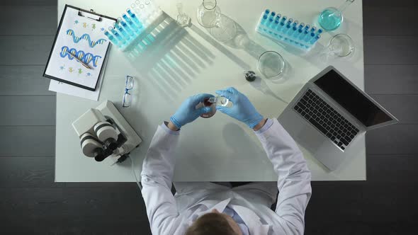 Chemist Mixing Different Chemical Agents and Writing Down Results on Computer