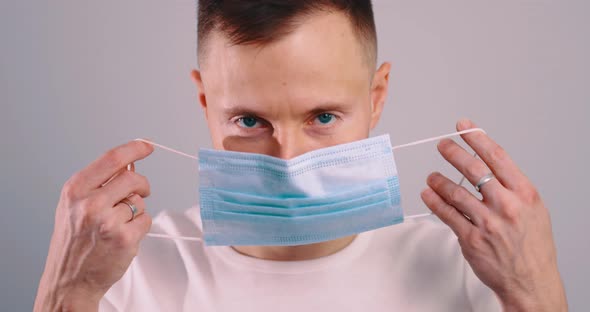 Young Handsome Caucasian Man Puts on Face Medical Mask