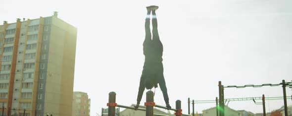 Sportsman Doing Handstand on Parallel Bars at Workout Playground