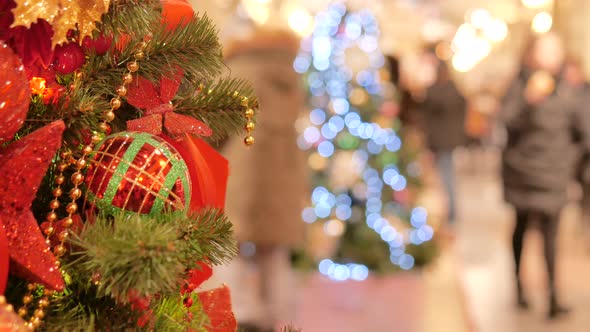 Festive Atmosphere in the Mall. In the Foreground Christmas Fir. Not in Focus People Walk and Buy