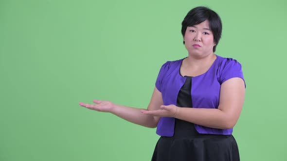 Stressed Young Overweight Asian Woman Showing Something