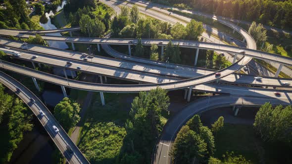 Rising Drone Time Lapse Over Freeway Interchange With Scenic Green Trees And River