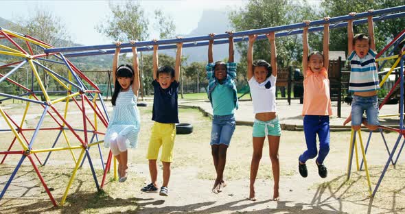 Happy schoolkids hanging on monkey bar