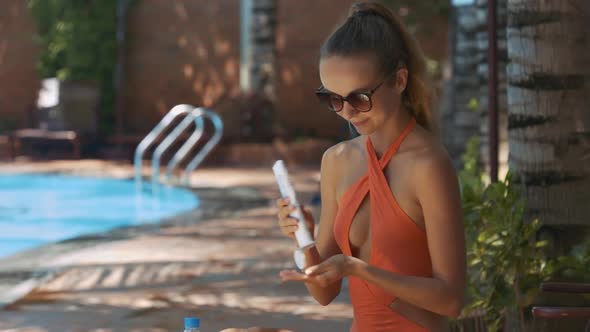 Girl Opens Sunscreen To Smear Body on Sunny Day