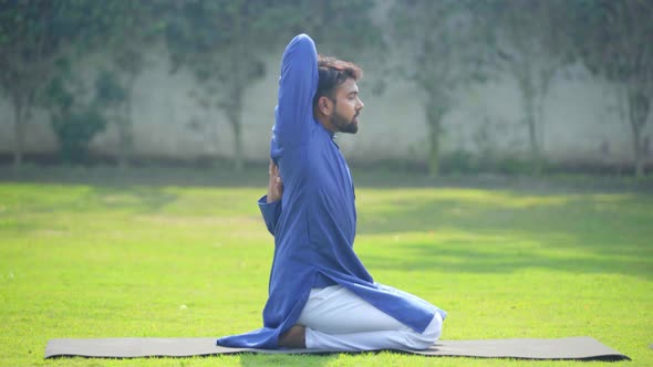 Indian man doing Gomukh asana or Cow Face Yoga Pose in an Indian traditional outfit Kurta Pajama