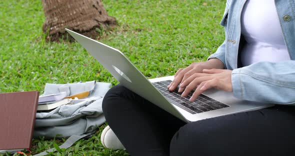 Woman Sitting In Park And Using Laptop