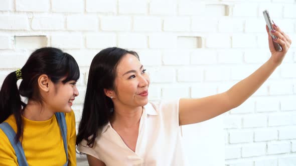 Happy Asian Teenage Daughter and Middleaged Mother Taking Selfie or Video Calling