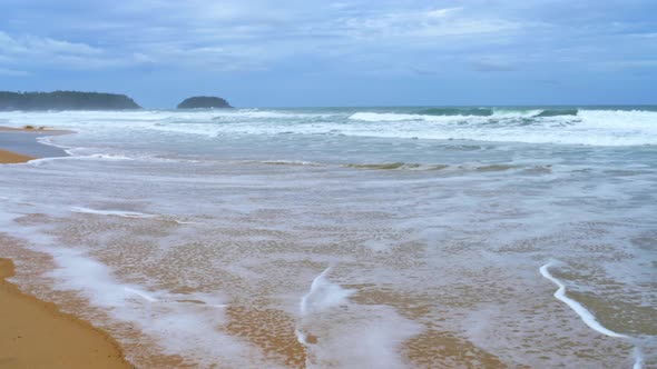 Landscapes view of waves breaking on beach sand and the sky on a stormy rainy season