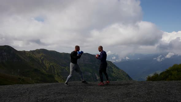 Two Men are Boxing Against the Background of Mountains